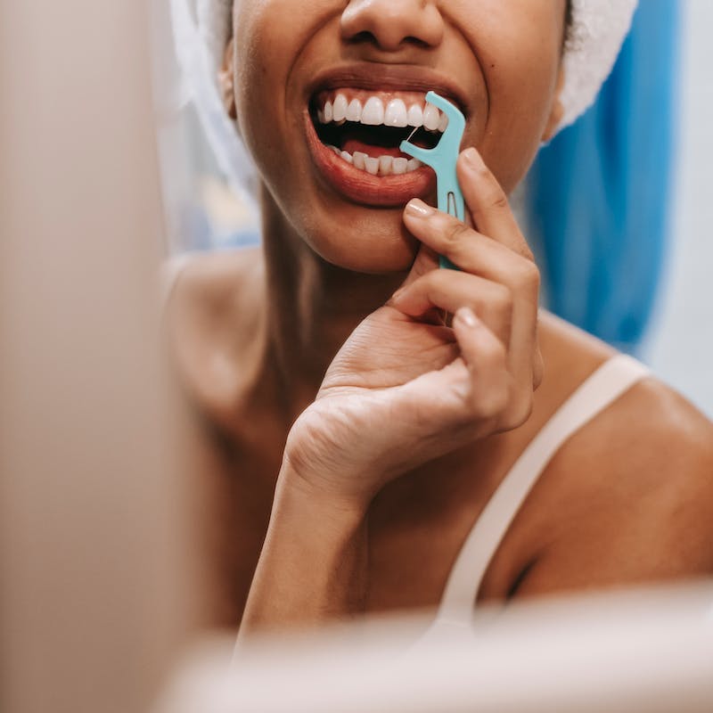 a woman flossing in front of a mirror