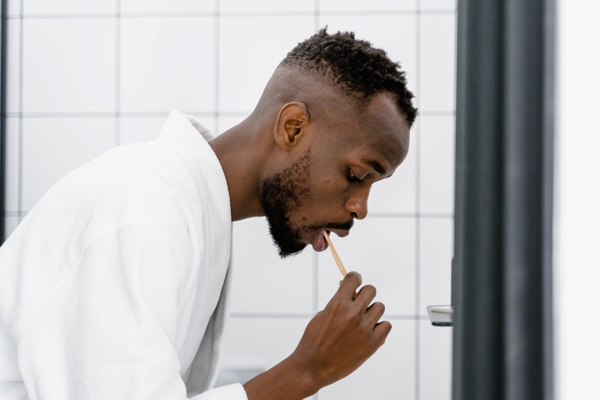 a man looking down while brushing his teeth