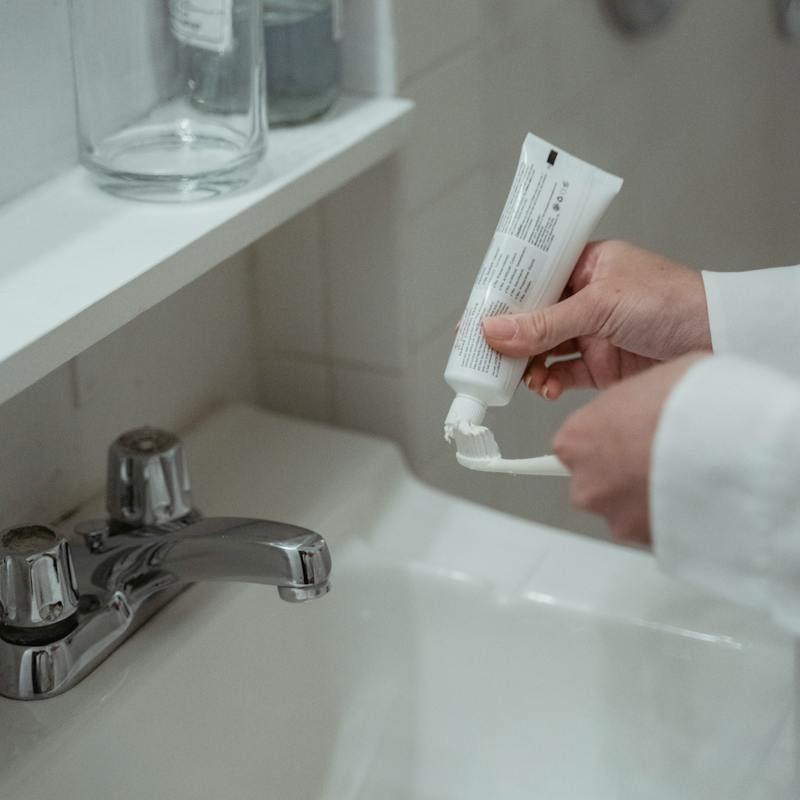 a person squeezing a tube of toothpaste on a toothbrush