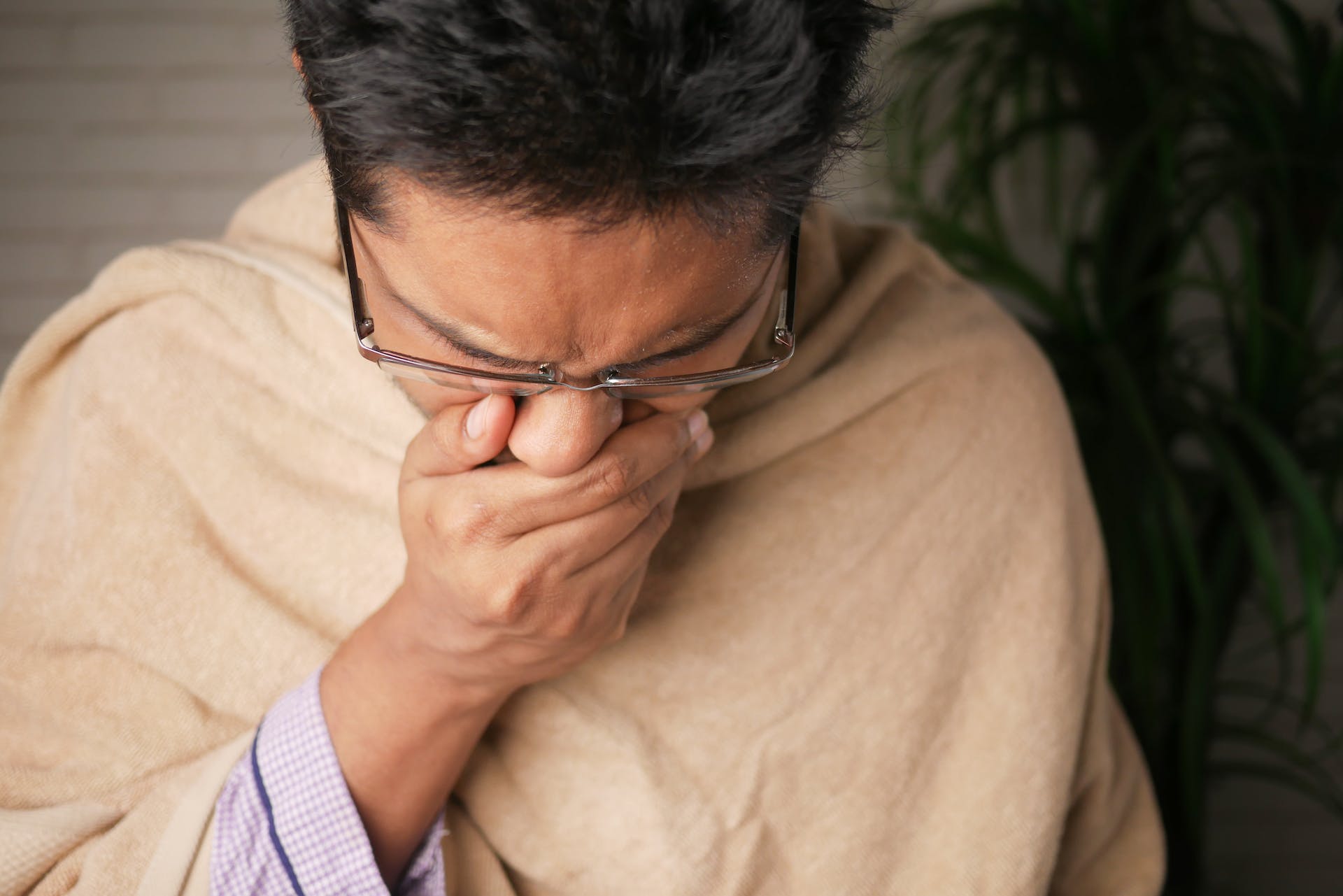 a man with cold covering his nose and mouth