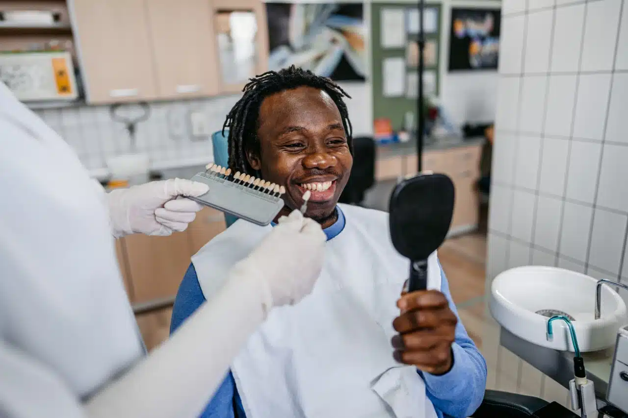 man choosing a shade of dental veneers at the dentist's office.