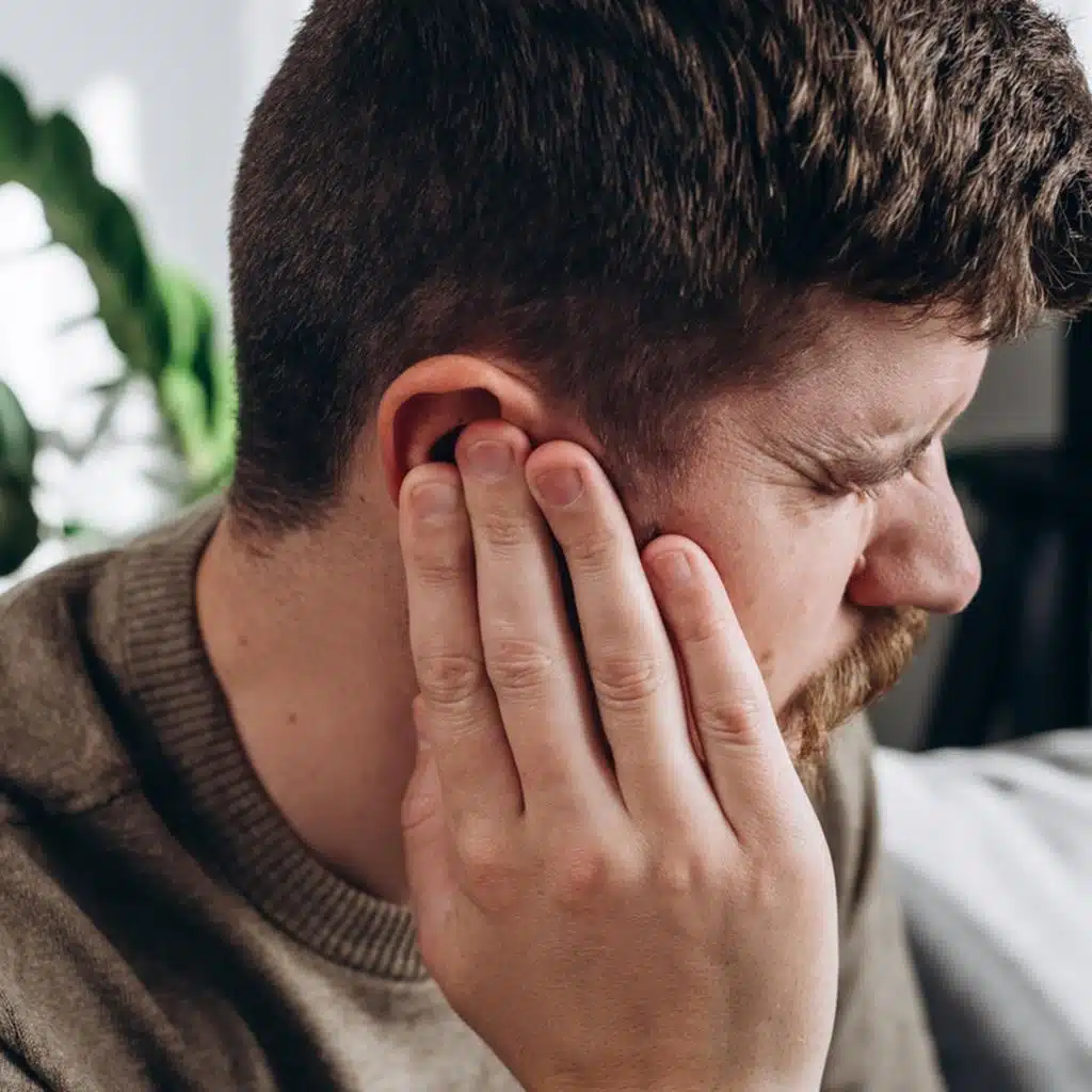 man lying in bed with severe toothache