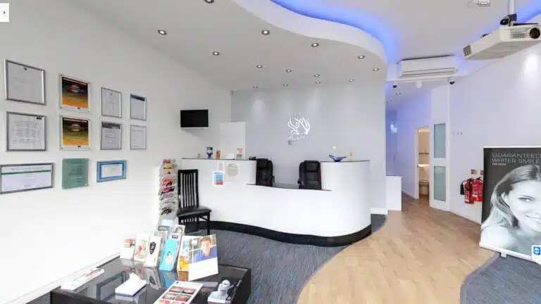 modern dental clinic reception area with a curved white desk and framed certifications.
