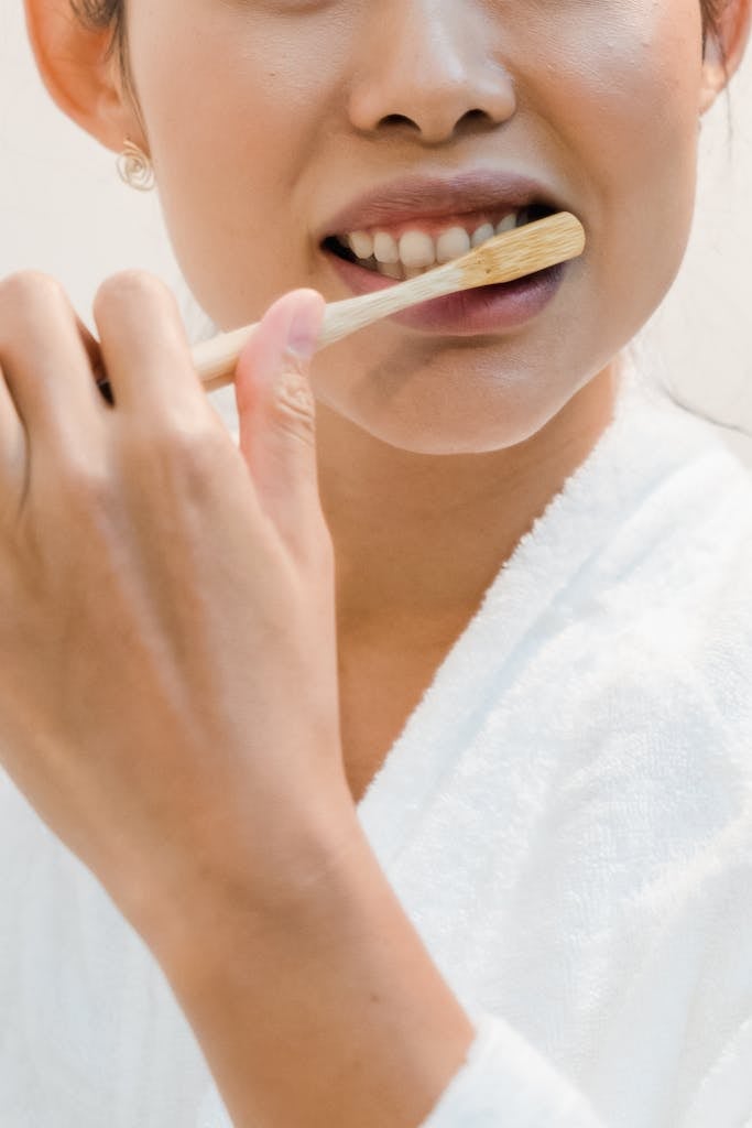 Tooth Surface Loss Treatment London a person brushing their teeth with an eco friendly bamboo toothbrush promoting oral hygiene. 9475393